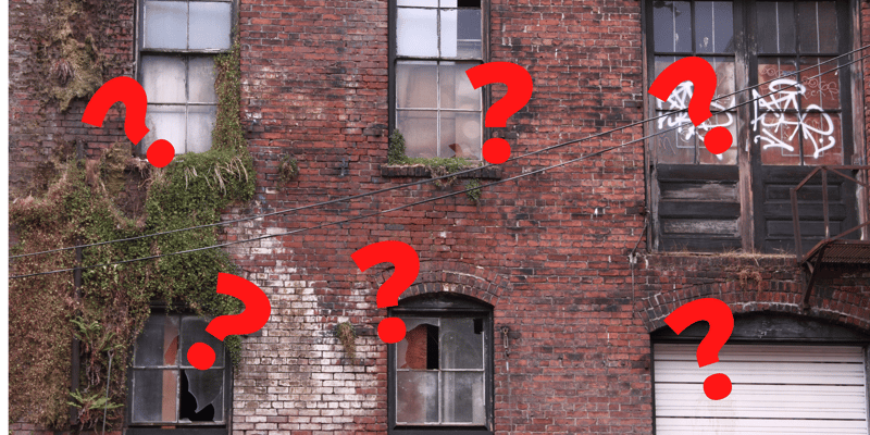 Blight.  An old building with question marks in red across the front of the picture.